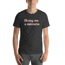 Load image into Gallery viewer, a model wearing a dark heather grey t-shirt with the caption 'hang on a minute' written in pearlescent letters