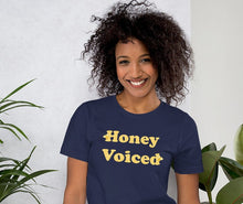 Load image into Gallery viewer, a model wearing a blue t-shirt with the caption 'honey voiced' written with honeycomb-patterned letters