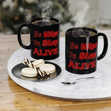 Load image into Gallery viewer, 11 oz  black ceramic coffee mug with the caption &#39;be wise to stay alive&#39; written in red letters
