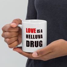 Load image into Gallery viewer, 11oz white ceramic mug with the caption &#39;love is a helluva drug&#39; in black and red letters
