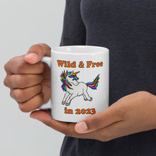 Load image into Gallery viewer, 11oz ceramic mug with a unicorn and the caption &#39;wild and free in 2023&#39;
