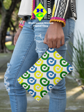 Load image into Gallery viewer, White pouch with blue, yellow and green spirals being held by a woman on the street viewed from the waist down.
