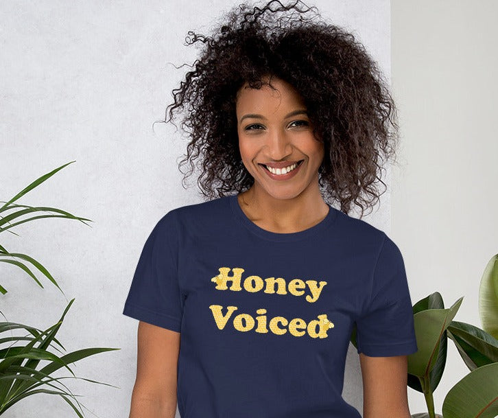 a model wearing a blue t-shirt with the caption 'honey voiced' written with honeycomb-patterned letters